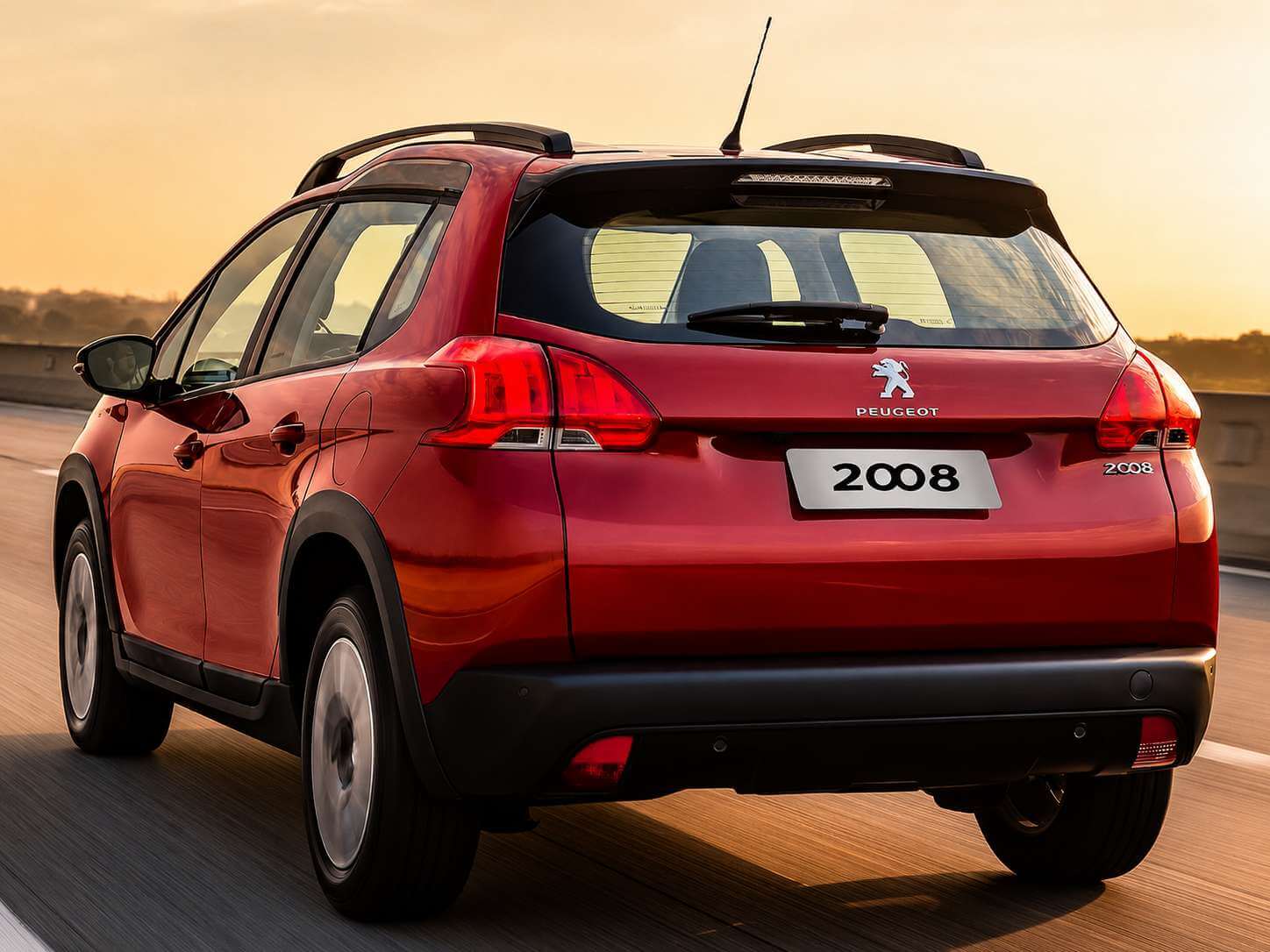 Peugeot 2008 vermelho da primeira geração brasileira fotografado de trás em três quartos, rodando por uma rodovia no fim da tarde. Na tampa tráseira aparecem o emblema do leão da Peugeot, a palavra PEUGEOT e o emblema 2008, além da placa com o nome do modelo. O carro tem barras longitudinais pretas no teto, antena tipo vareta e rodas de liga leve claras, com o sol baixo e dourado iluminando a pista ao fundo.