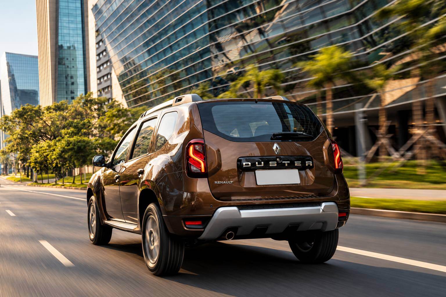 Renault Duster Dynamique 1.6 2019 marrom visto de tres quartos traseiro, em movimento numa avenida arborizada de uma grande cidade, ao lado de predios de vidro; a luz quente do fim de tarde destaca as lanternas verticais, a letra DUSTER na tampa do porta-malas e o protetor prateado no para-choque.